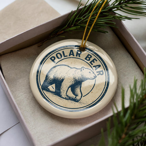 A circular ornament with the word "Polar Bear" printed on it, placed inside a box with pine branches.