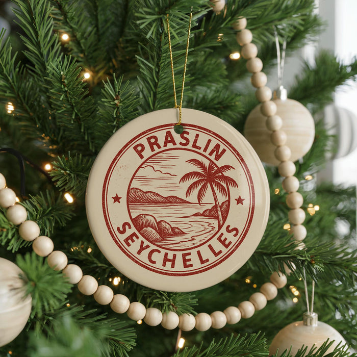 A Christmas tree decorated with ornaments, including a circular ornament with the text "Praslin Seychelles" and a palm tree design.
