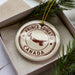 A white ornament with the text "PRINCE EDWARD CANADA" printed on it, surrounded by pine branches.