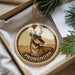 A round ornament with a deer image and the word "PRONGHORN" printed on it, placed in a box with pine branches.