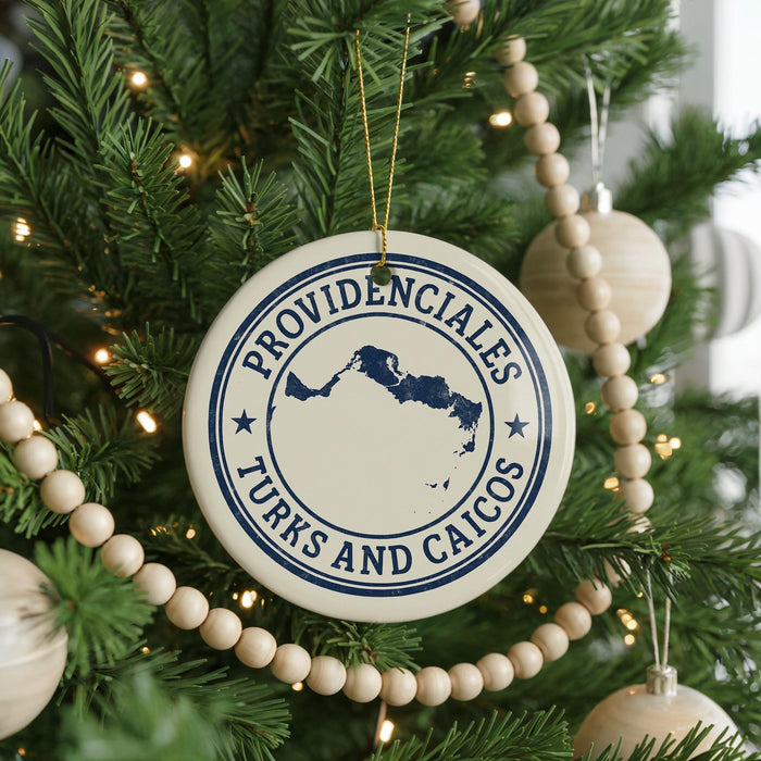 A Christmas tree decorated with ornaments, including a circular ornament with the text "PROVIDENCIALES TURKS AND CAICOS" and a wooden bead decoration.