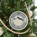 A Christmas tree decorated with ornaments, including a circular ornament with the text "PROVIDENCIALES TURKS AND CAICOS" and a wooden bead decoration.