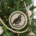 A Christmas tree decorated with ornaments, including a circular ornament featuring a bird design.