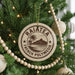 A round ornament on a Christmas tree, featuring the text "RAIATEA FRENCH POLYNESIA" and a palm tree illustration.