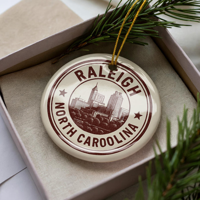 A circular ornament with the text "RALEIGH NORTH CAROLINA" printed on it, surrounded by pine branches.