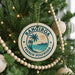 A round ornament on a Christmas tree, featuring a palm tree and a sunset, with the text "Rangiroa" and "French Polynesia" printed on it.