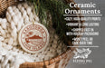 Ceramic ornaments, featuring a round ornament with a palm tree and a mountain, hanging in a basket with a pine branch.