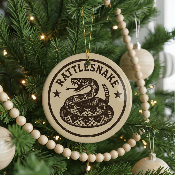 A Christmas tree decorated with ornaments, including a round ornament with a snake design and the text "Rattlesnake" on it.