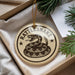 A decorative ornament in a box, featuring a snake design with the text "Rattlesnake" on it.