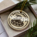 A decorative ornament in a box, featuring a snake design with the text "Rattlesnake" on it.