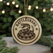 A round ornament with the text "RATTLESNAKE" and a snake design, hanging from a string.