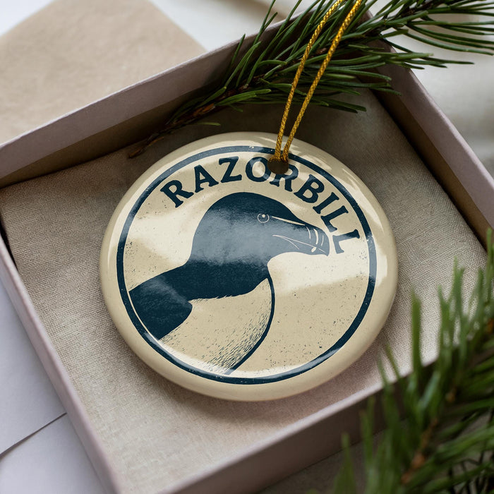 A circular ornament with the word "RAZORBILL" printed on it, surrounded by pine branches.