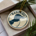 A circular ornament with the word "RAZORBILL" printed on it, surrounded by pine branches.