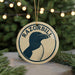 A circular ornament with the word "RAZORBILL" and a graphic of a penguin is displayed on a table, surrounded by pine branches and twinkling lights.