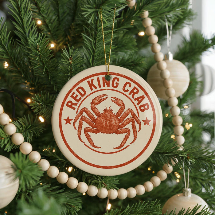 A Christmas tree decorated with ornaments, including a large circular ornament with a red crab design and the text "RED KING CRAB" on it.