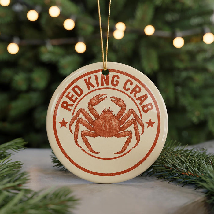 A round ornament with the text "RED KING CRAB" and an illustration of a crab is displayed in front of a Christmas tree with twinkling lights.