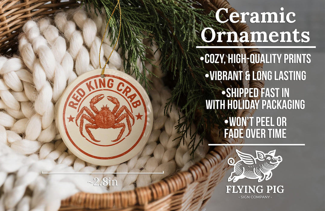Ceramic ornaments, featuring a ceramic crab ornament with a red crab and text, are displayed in a woven basket.