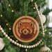 A Christmas tree decorated with ornaments, including a wooden ornament featuring a red panda face.