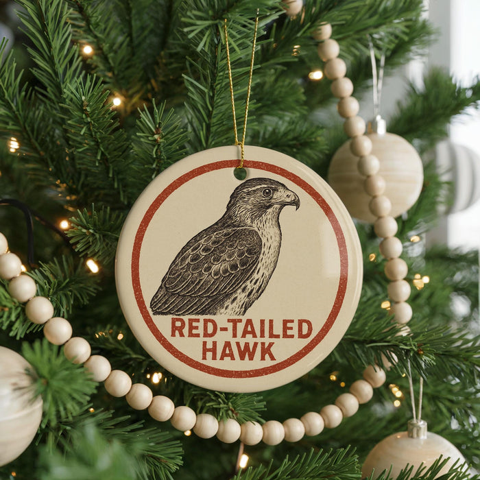 A Christmas tree decorated with ornaments, including a circular ornament with a red-tailed hawk image and the text "RED-TAILED HAWK" on it.