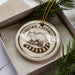 A ceramic ornament in a box, featuring a raccoon illustration and the text "Ringtail Cacomistle".