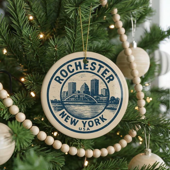 A circular ornament on a Christmas tree, featuring the text "Rochester, New York" and a graphic of a bridge.