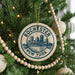 A circular ornament on a Christmas tree, featuring the text "Rochester, New York" and a graphic of a bridge.