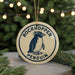 A round ornament with a penguin design, featuring the text "ROCKHOPPER PENGUIN" on it, is hanging from a string.