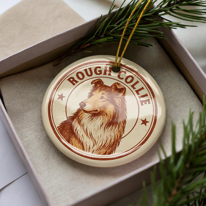A circular ornament featuring a collie dog, with the text "ROUGH COLLIE" printed on it, is displayed in a box surrounded by pine branches.