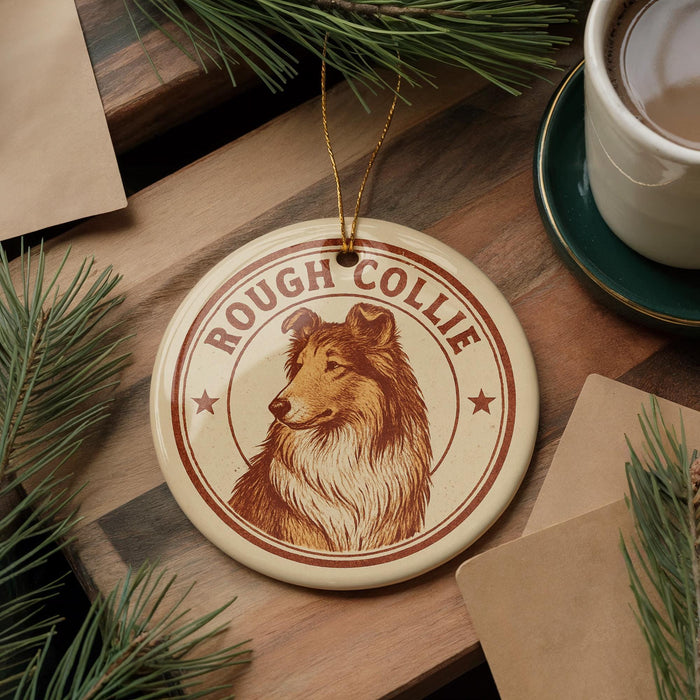 A round ornament featuring a collie dog, with the text "ROUGH COLLIE" printed on it, is displayed on a wooden surface alongside a cup of coffee and some pine branches.