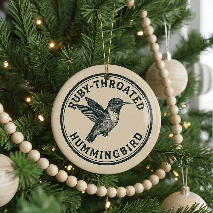 A round ornament on a Christmas tree, featuring a hummingbird design and the text "Ruby-throated Hummingbird".