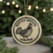 A round ornament with a black and white illustration of a bird, likely a grouse, and the text "RUFFED GROUSE" on it, hanging from a string.