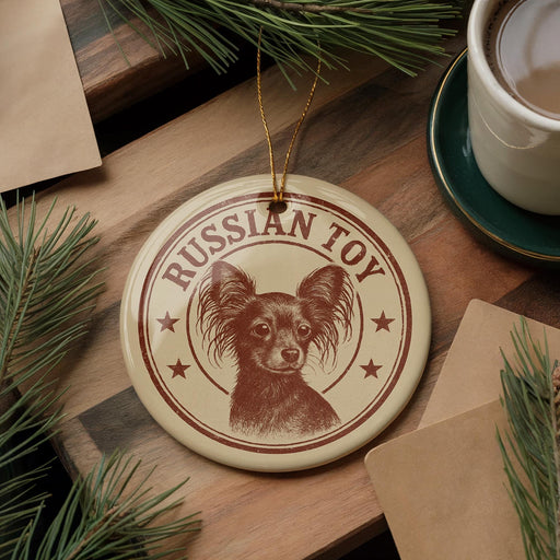 A round ornament featuring a dog's face with the text "Russian Toy" is displayed on a wooden surface, surrounded by pine branches and a cup of coffee.