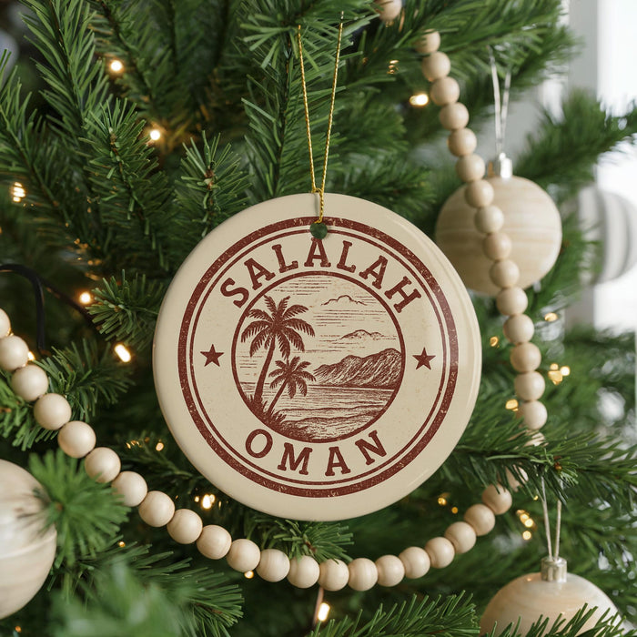 A Christmas tree decorated with ornaments, including a circular ornament with the text "Salalah Oman" and a palm tree design.