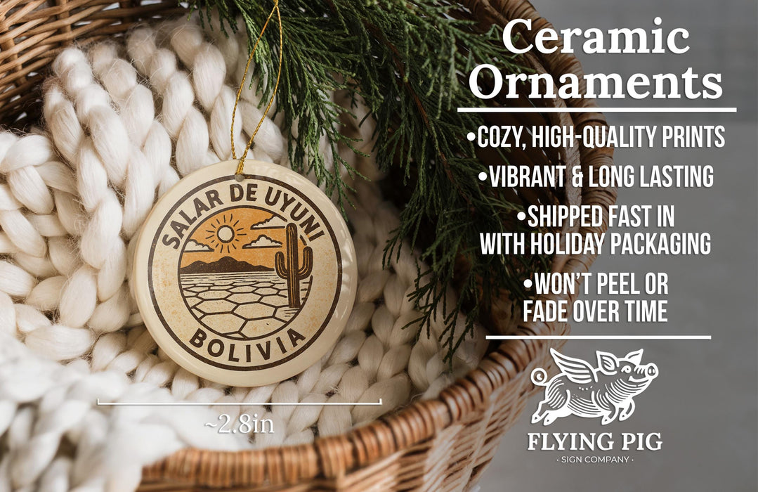 Ceramic ornaments, specifically a Bolivia ornament, are displayed in a woven basket. The ornament features a sun and a cactus design, and it is described as a cozy, high-quality print, vibrant, and long-lasting. The ornament is shipped fast in holiday packaging and does not peel or fade over time. The image also includes a scale for the ornament, indicating it is 2.8 inches in diameter.