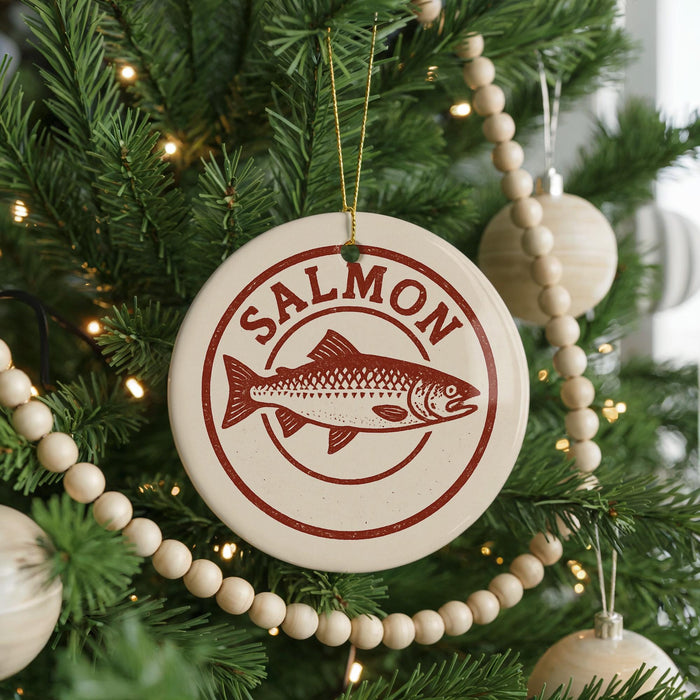 A Christmas tree decorated with ornaments, including a round ornament with a salmon design and the word "Salmon" written on it.