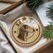 A round ornament with a dog's head and the word "Saluki" printed on it, hanging from a string.