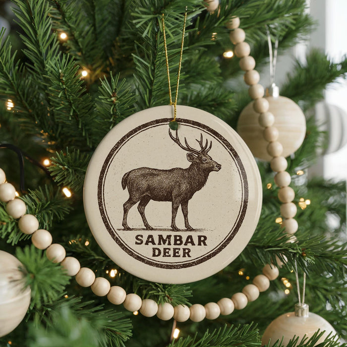 A Christmas tree decorated with ornaments, including a circular ornament with a deer image and the text "SAMBAR DEER".