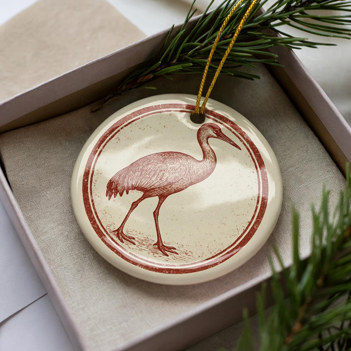 A ceramic ornament in the shape of a bird, possibly a crane, is displayed in a box with pine branches.