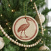 A Christmas tree decorated with ornaments, including a circular ornament featuring a red bird silhouette.
