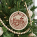 A round ornament on a Christmas tree, featuring the text "SARAJEVO BOSNIA AND HERZEGOVINA" and an illustration of a bridge.