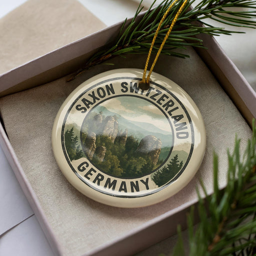 A decorative ornament in a box, featuring a scenic image of Saxon Switzerland and Germany.