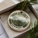 A decorative ornament in a box, featuring a scenic image of Saxon Switzerland and Germany.
