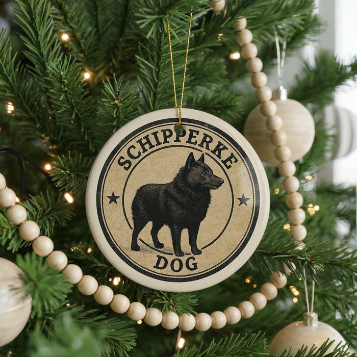 A Christmas tree decorated with ornaments, including a circular ornament with a black dog image and the text "SCHIPPERKE DOG" around the edge.