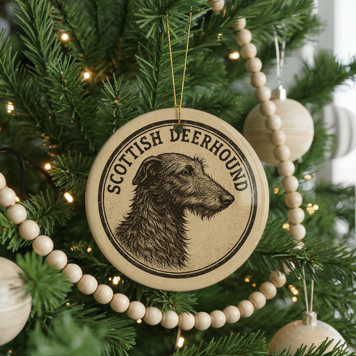 A circular ornament featuring a Scottish Deerhound dog is hanging on a Christmas tree, surrounded by other ornaments and lights.