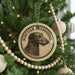 A circular ornament featuring a Scottish Deerhound dog is hanging on a Christmas tree, surrounded by other ornaments and lights.