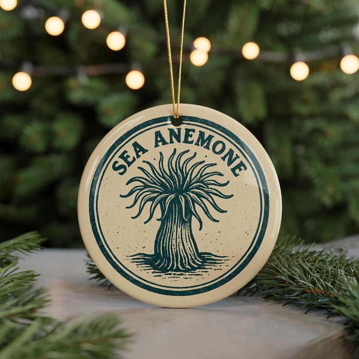A circular ornament with the text "SEA ANEMONE" and an illustration of an anemone is displayed in front of a blurred Christmas tree with lights.