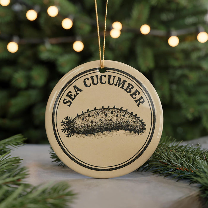 A round ornament with the text "SEA CUCUMBER" and an illustration of a sea cucumber on it, hanging from a string.