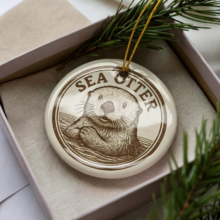 A decorative ornament featuring a close-up image of a sea otter, with the word "SEA Otter" written around the image.