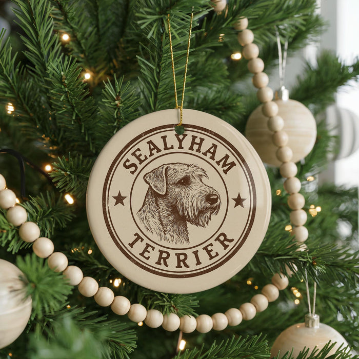 A Christmas tree decorated with ornaments, including a circular ornament with a dog's head and the text "SEALYHAM TERRIER" printed on it.