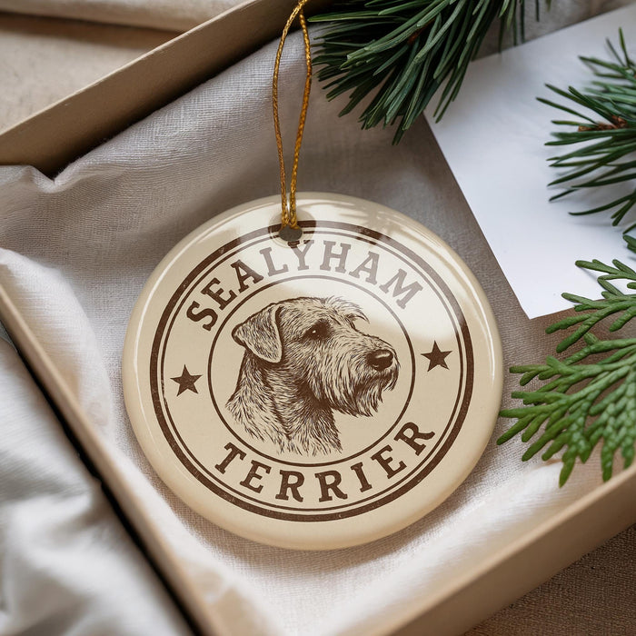 A round ornament with the text "SEALYHAM TERRIER" and a dog's head image is displayed in a box with pine branches.